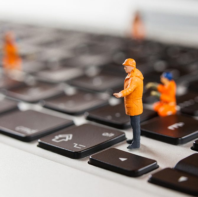 Conceptual image of miniature workmen repairing a laptop keyboard